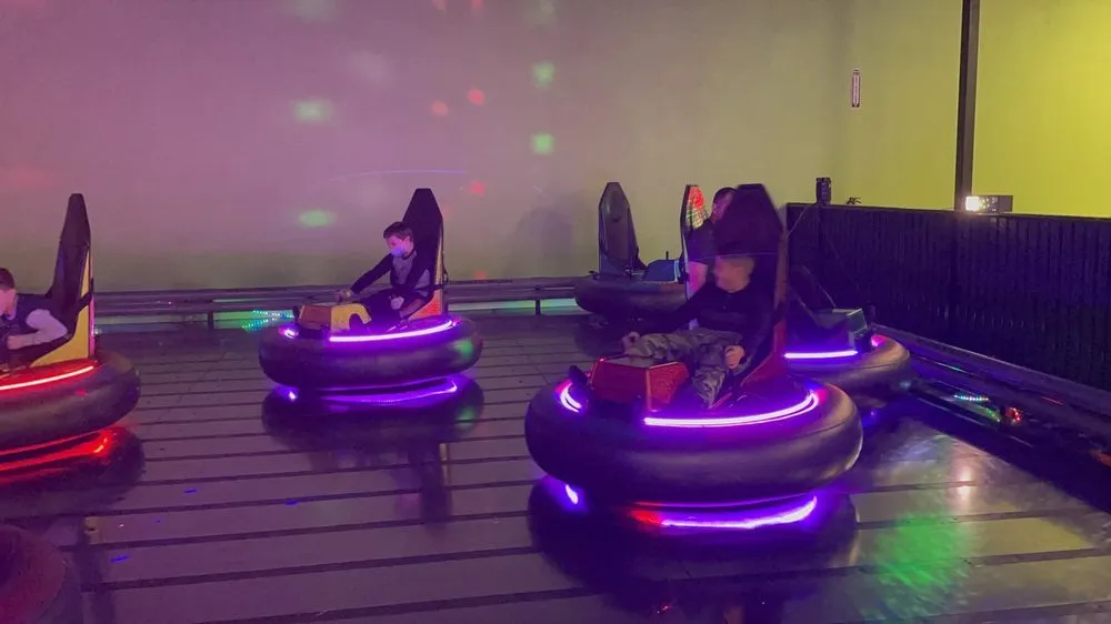 Kids riding bumper cars under neon lights at SacTag.