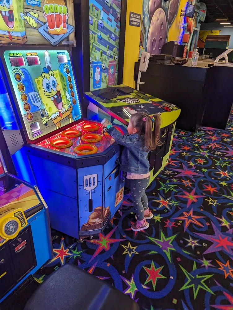 Toddler playing arcade game at SacTag family entertainment center.